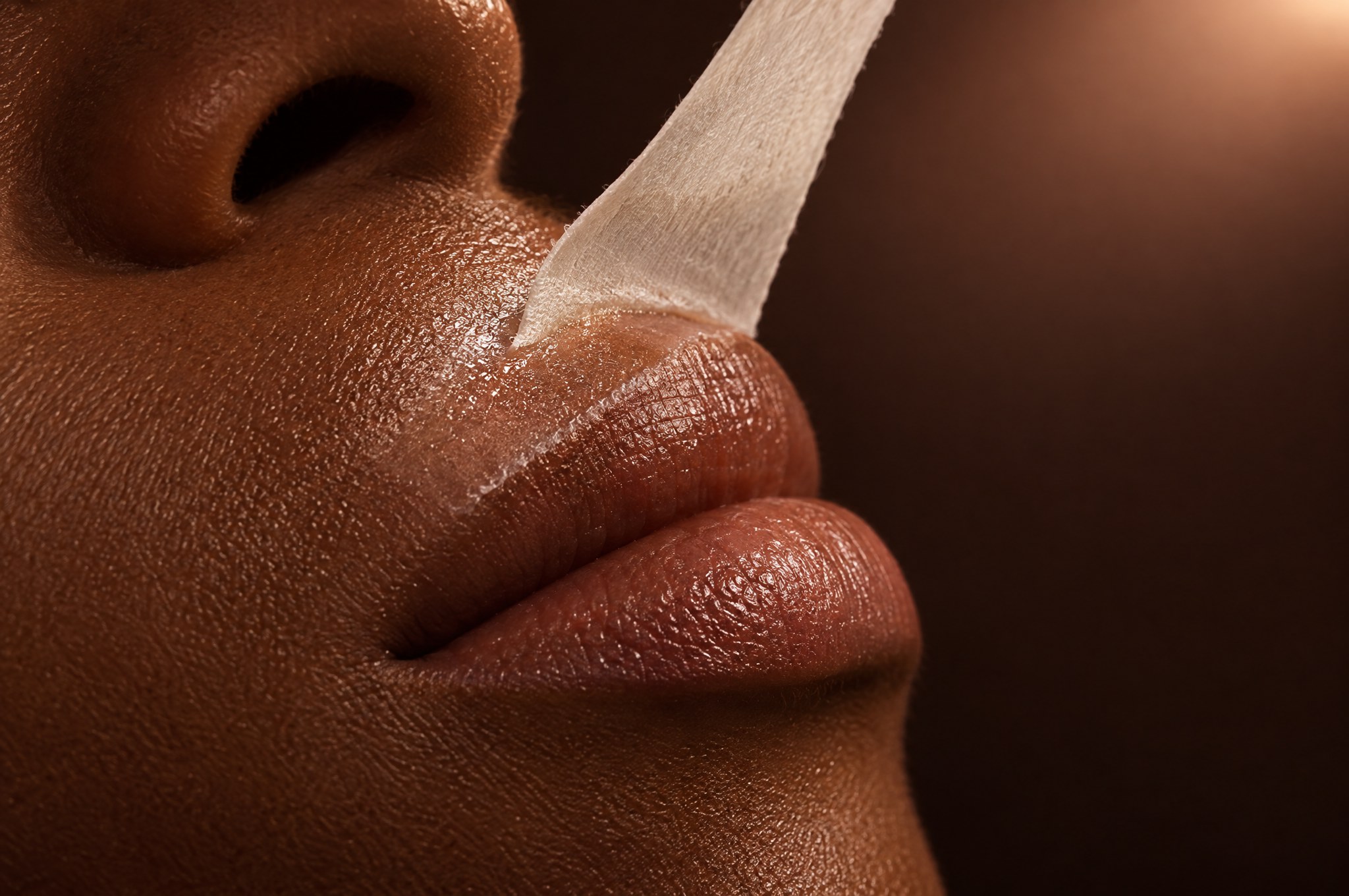 A small wax strip lifting gently from the upper lip, the Upper Lip Wax at Glo Haus by Alanii, Orlando